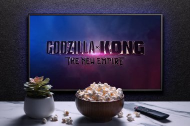 Godzilla x Kong Yeni İmparatorluk fragmanı ya da TV ekranındaki film. Uzaktan kumandalı televizyon, patlamış mısır kasesi ve ev bitkisi. Astana, Kazakistan - 22 Mart 2024.