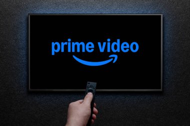 TV ekranında Amazon Prime Video logosu. Adam uzaktan kumandayla televizyonu açıyor. Amerikan aboneliği medya hizmeti. Astana, Kazakistan - 23 Kasım 2024.