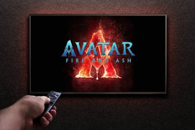 Adam uzaktan kumandayla televizyonu açıyor. TV ekranında Avatar Fire ve Ash fragmanı ya da film oynanıyor. Astana, Kazakistan - 5 Şubat 2025.