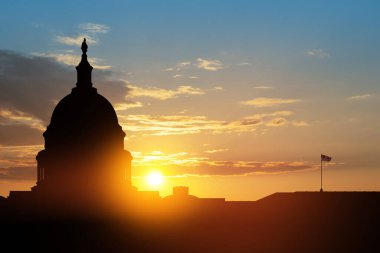 ABD Kongre Binası, gün batımında Washington DC 'de uçan kuşlarla gökyüzünün arka planında siluet inşa ediyor..