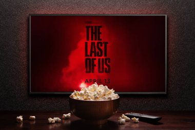 TV ekranında The Last of Us 2. Sezon fragmanı ya da film gösteriliyor. Uzaktan kumandalı televizyon, patlamış mısır kasesi. Oyunun film uyarlaması. Astana, Kazakistan - 4 Nisan 2023.