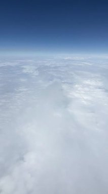 Mavi gökyüzünde beyaz bulutlar. Bir uçağın penceresinden bak. Üst hava manzarası bulutlu. Havadan kuş gözü. Yukarıdan bak. Dikey video.