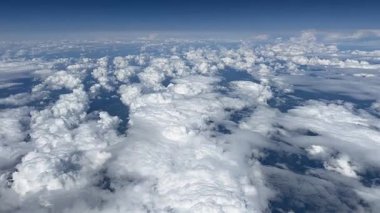 Mavi gökyüzünde beyaz bulutlar. Bir uçağın penceresinden bak. Üst hava manzarası bulutlu. Havadan kuş gözü. Yukarıdan görüntüle.