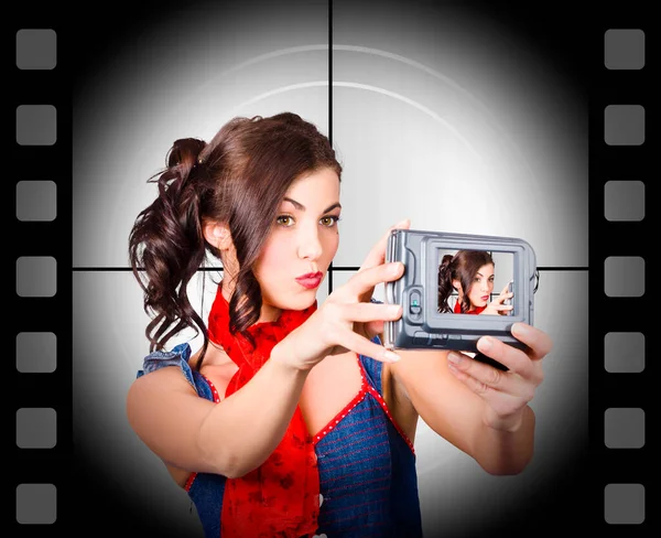 Young woman recording a movie of herself using video camera. Old cinema background