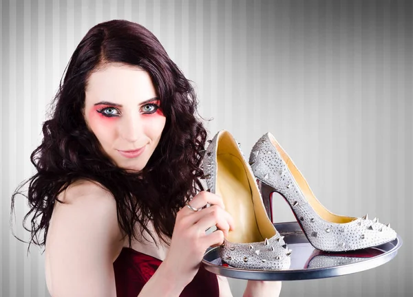 Beautiful fashion sales woman wearing bright make-up holding a silver platter of shoes when selling luxurious evening attire