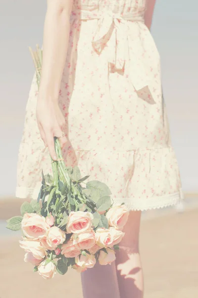 Pastel toned retro scene of a romantic lady holding a beach bouquet of fresh flower love