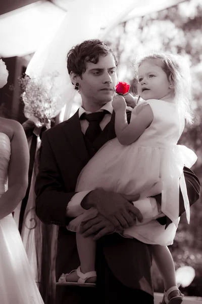 Handsome Father Wearing Tuxedo Holding His Daughter In His Arms And Looking At Her With Love And Concern For Her Future