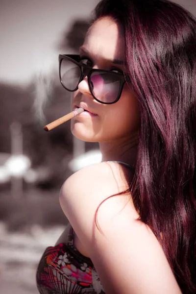 Fashion Portrait Of A Smoking Hot Woman Inhaling Nicotine From A Cigar Or Cigarette While Wearing Fashionable Sunglasses At A Outdoor Location