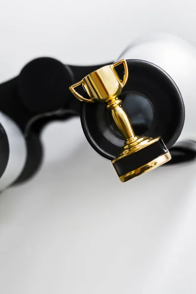 Closeup of small gold colored trophy and sports binoculars. Sport and business concept