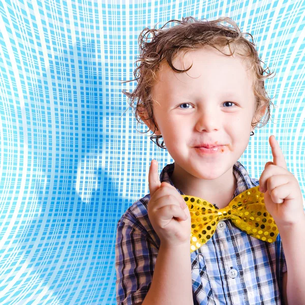Cute smiling child with chocolate covered face pointing up in approval for Easter time. On blue abstract background