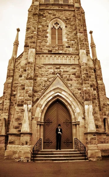 Creepy Vintage Man Wearing Top Hat Stands At A Closed Church Door, Locked Out Of A Service As He Is Late For His Own Funeral
