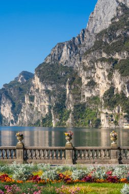 Riva del Garda, İtalya: Çiçekler, dağlar ve taş bir balustrade ile manzaralı göl kenarı