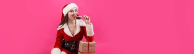 Kırmızı arka planda Noel Baba kostümü giymiş güzel bir kadın..