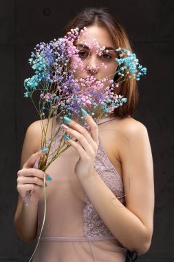 Zarif, çıplak bir beden giymiş güzel seksi bir bayan elinde çiçekler tutuyor. Moda mankeni kızın güzel portresi stüdyoda..