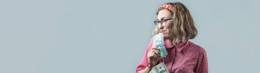 Gri arka plan üzerinde elinde Amerikan doları para ile gözlük kırmızı ekose gömlek genç güzel kadın Closeup.