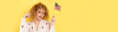 Yüzünde bir gülümseme olan genç mutlu bir kız ellerinde bir Amerikan bayrağı tutuyor. Vatanseverliğin ve özgürlüğün sembolü..