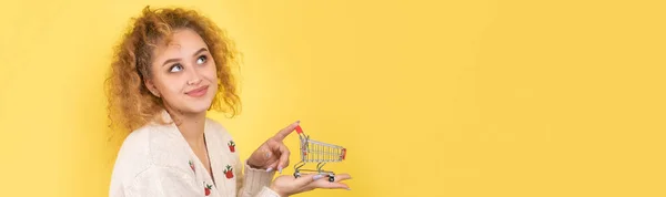 若い美しい巻き毛の少女は 彼女の手に食品カートを保持しています ショッピングのコンセプト — ストック写真