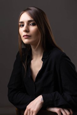 Stüdyoda uzun saçlı genç bir esmerin portresi. Koyu renkli dramatik fotoğraf.