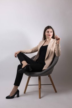 Stüdyoda uzun saçlı genç bir esmerin portresi. Beyaz arka planda sandalyede oturan tatlı kız..