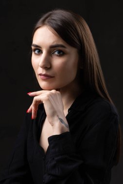 Stüdyoda uzun saçlı genç bir esmerin portresi. Koyu renkli dramatik bir fotoğraf. Kolunda yılan dövmesi olan bir kız..