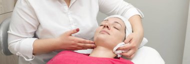 Yüz bakımı. Güzellik uzmanı güzellik salonunda fırça kullanarak yüzüne güzellik maskesi takıyor.