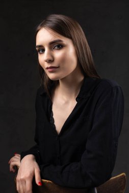 Stüdyoda uzun saçlı genç bir esmerin portresi. Koyu renkli dramatik fotoğraf.