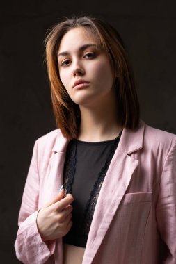 Siyah dantelli bluz giyen bir kız stüdyoda gri bir koltukta poz veriyor..