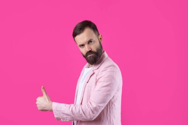 Pembe ceketli, sakallı bir adam başparmak gösteriyor..