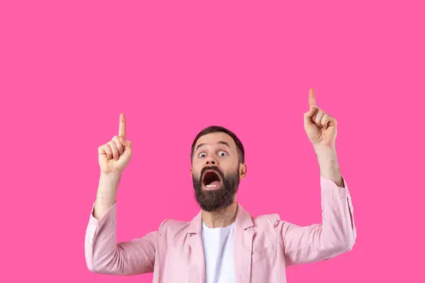 一个穿着粉色夹克的男人在粉红色孤立的背景上指明了方向 免版税图库图片