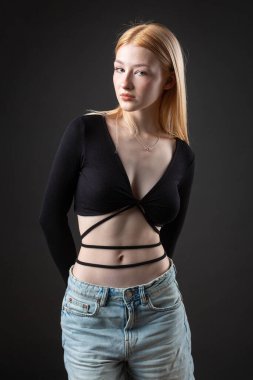 Stüdyoda seksi bluzlu ve kot şortlu sarışın bir kadının portresi..