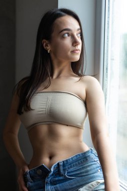 Güzel bir esmer stüdyoda bluz ve kot pantolon giyerek poz veriyor..