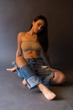 Güzel bir esmer stüdyoda bluz ve kot pantolon giyerek poz veriyor..