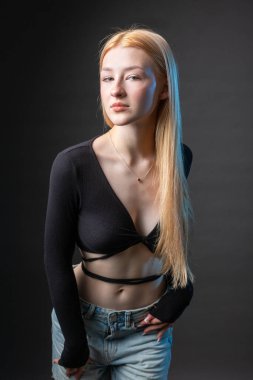 Stüdyoda seksi bluzlu ve kot şortlu sarışın bir kadının portresi..
