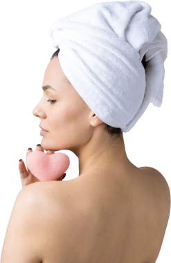 Kafasında beyaz havluyla güzel bir kadın portresi ve pembe bir kalbe bakan bir vücut için sünger. Cilt temizleme eko organik kozmetik rahatlama konsepti.