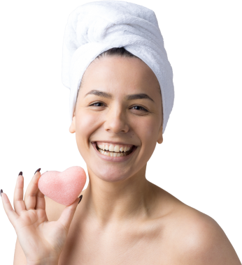 Kafasında beyaz havluyla güzel bir kadın portresi ve pembe bir kalbe bakan bir vücut için sünger. Cilt temizleme eko organik kozmetik rahatlama konsepti.