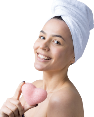 Kafasında beyaz havluyla güzel bir kadın portresi ve pembe bir kalbe bakan bir vücut için sünger. Cilt temizleme eko organik kozmetik rahatlama konsepti.