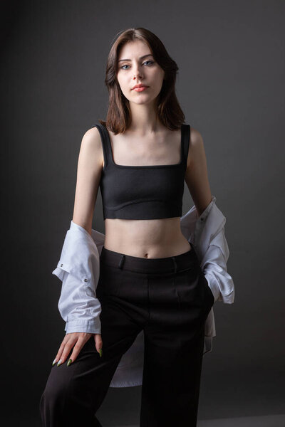 Молодая девушка в белой рубашке и черном галстуке в студии.