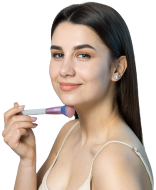 Açık renk bluzlu, beyaz arka planda yüz makyajı yapan genç bir kızın yakın çekimi. Güzel bir kadın yüzüne bir makyaj fırçası tutar ve gülümser..