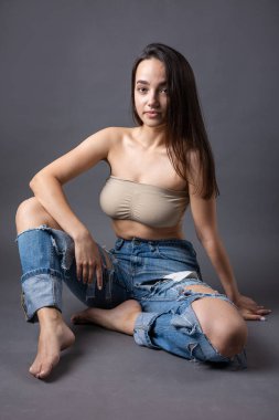 Güzel bir esmer stüdyoda bluz ve kot pantolon giyerek poz veriyor..