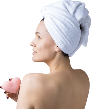 Kafasında beyaz havluyla güzel bir kadın portresi ve pembe bir kalbe bakan bir vücut için sünger. Cilt temizleme eko organik kozmetik rahatlama konsepti.