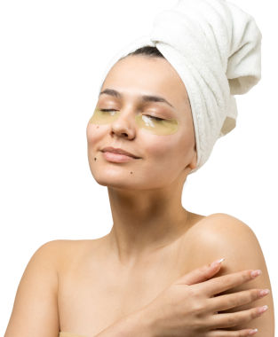 Kafasında beyaz havluyla gezen genç bir kız gözlerinin altına kolajen jel bantlar takıyor. Göz teması altında maske.