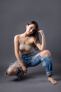 Güzel bir esmer stüdyoda bluz ve kot pantolon giyerek poz veriyor..