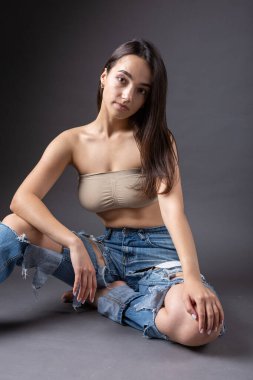 Güzel bir esmer stüdyoda bluz ve kot pantolon giyerek poz veriyor..