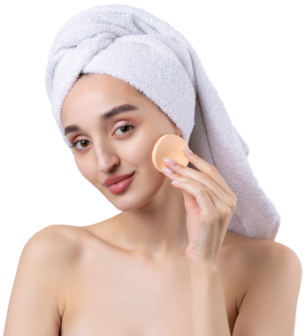 Kalın kaşlı güzel bir kız, beyaz arka planda mükemmel bir ten, kafasında havlu, güzel bir fotoğraf. Kozmetik sünger tutuyor..