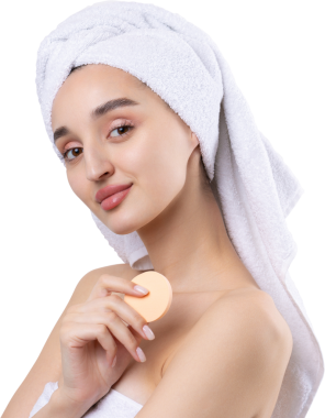 Kalın kaşlı güzel bir kız, beyaz arka planda mükemmel bir ten, kafasında havlu, güzel bir fotoğraf. Kozmetik sünger tutuyor..