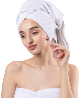 Kalın kaşlı güzel bir kız, beyaz arka planda mükemmel bir ten, kafasında havlu, güzel bir fotoğraf. Kozmetik rulo tutuyor..