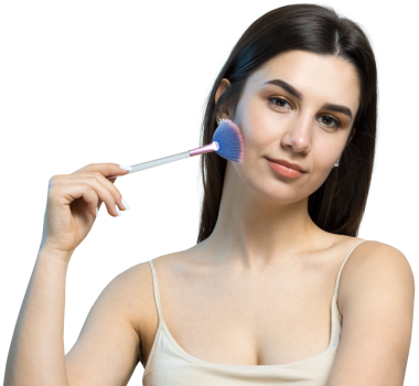 Açık renk bluzlu, beyaz arka planda yüz makyajı yapan genç bir kızın yakın çekimi. Güzel bir kadın yüzüne bir makyaj fırçası tutar ve gülümser..