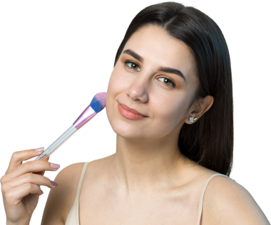 Açık renk bluzlu, beyaz arka planda yüz makyajı yapan genç bir kızın yakın çekimi. Güzel bir kadın yüzüne bir makyaj fırçası tutar ve gülümser..