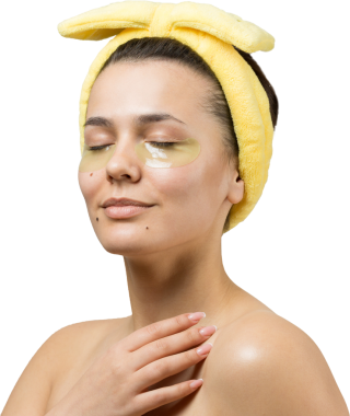 Kafasında beyaz havluyla gezen genç bir kız gözlerinin altına kolajen jel bantlar takıyor. Göz teması altında maske.