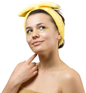 Kafasında beyaz havluyla gezen genç bir kız gözlerinin altına kolajen jel bantlar takıyor. Göz teması altında maske.